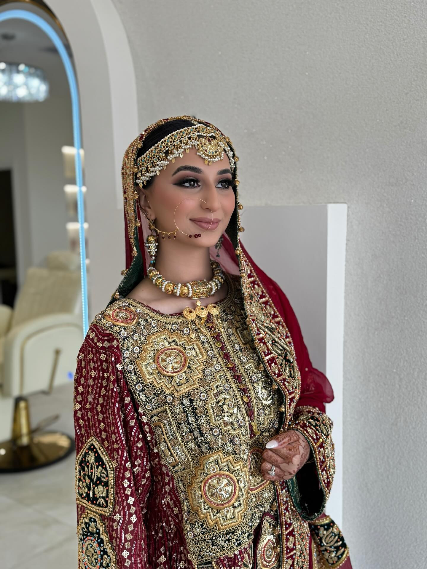 A bride in traditional red and gold attire with a jewelled headpiece